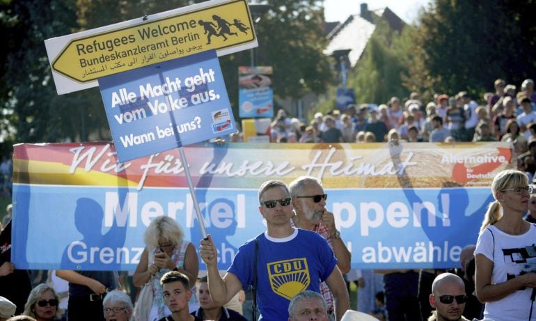 Simpatizantes del partido ultraderechista Alternativa para Alemania (AfD) portan pancartas contra la canciller alemana, Angela Merkel.