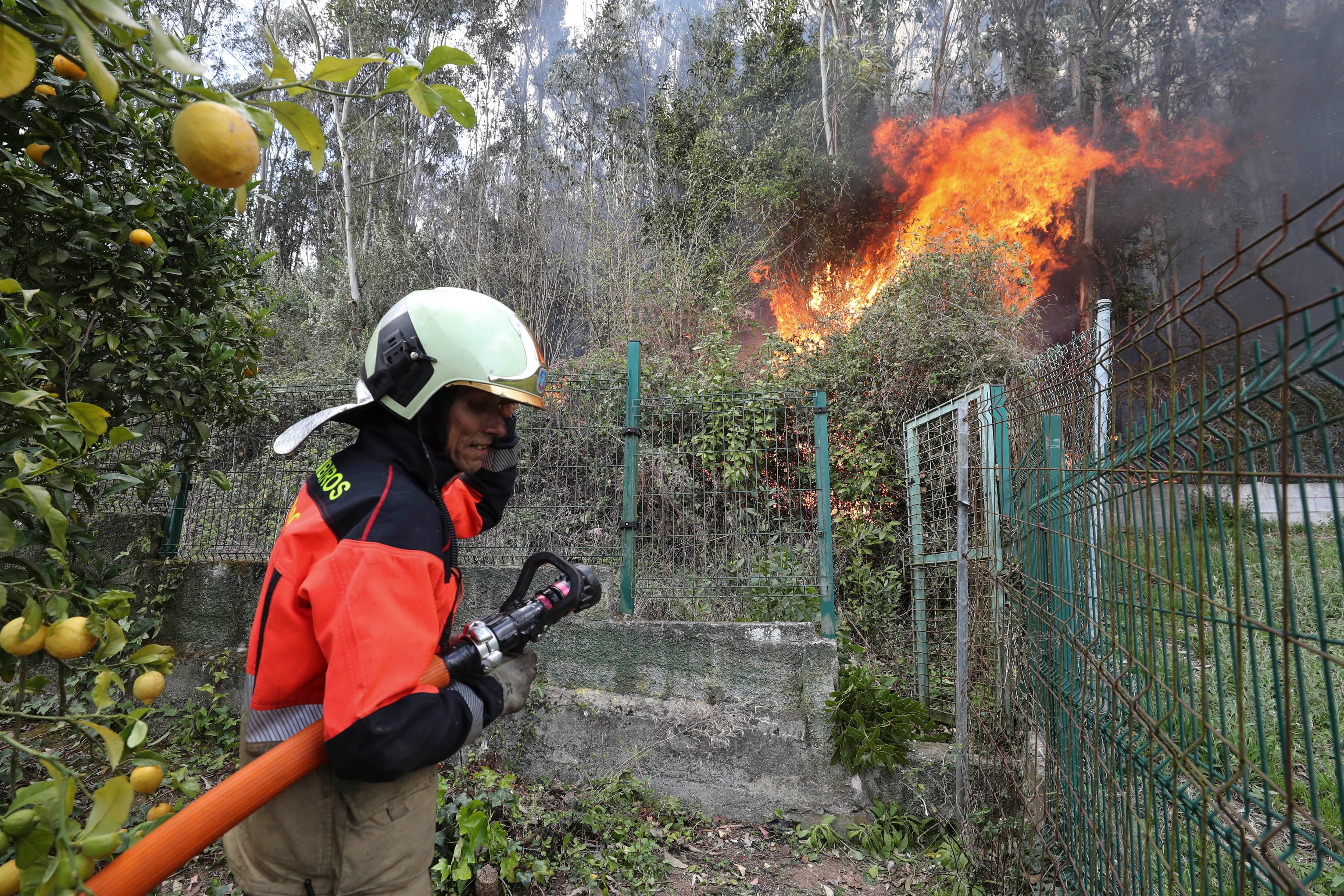 OVIEDO, 31/03/2023.- Bomberos de Oviedo protegen dos casas de las llamas del incendio registrado la pasada noche en el Monte Naranco de Oviedo, donde tuvieron que ser desalojadas 65 personas de los núcleos de Cuyences y Fitoria. EFE/J.L.Cereijido
