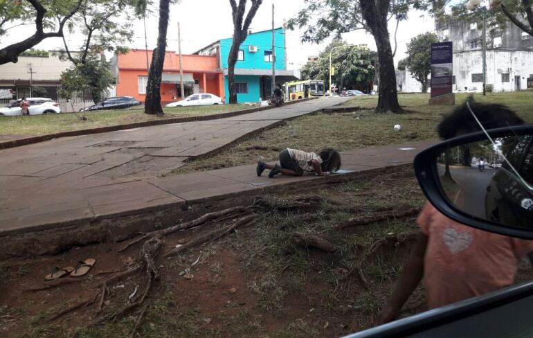 Una niña bebe agua de un charco del suelo en Posadas (Argentina)