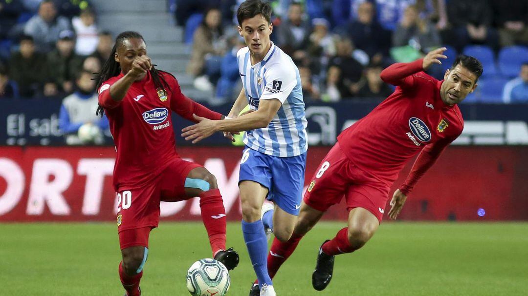 El malagueño Juanpi intenta salir airoso del acoso de Emmanuel y Márquez, del C.F. Fuenlabrada, durante el partido de la primera vuelta en La Rosaleda.