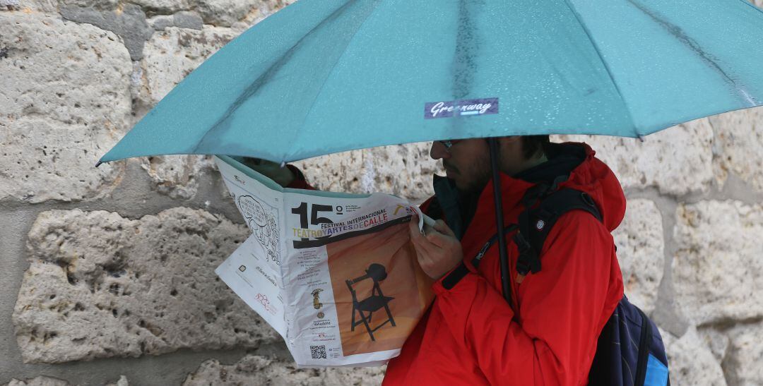 Un joven se protege de la lluvia con un paraguas