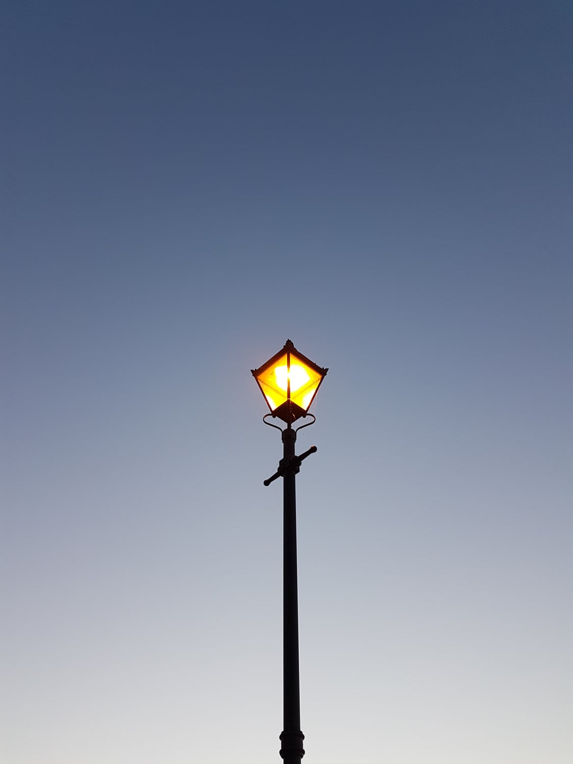 Una farola encendida al atardecer