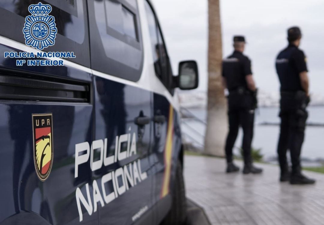 Agentes de la Policía Nacional junto a un coche patrulla.