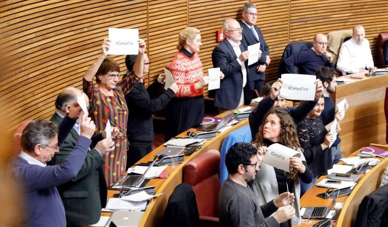 Los diputados de Podemos muestran carteles con el lema &quot;#Campsfora&quot; en el pleno de Les Corts Valencianes tras la votación de la propuesta de Compromís para instar al expresident de la Generalitat Francisco Camps a renunciar como miembro del Consell Jurídi