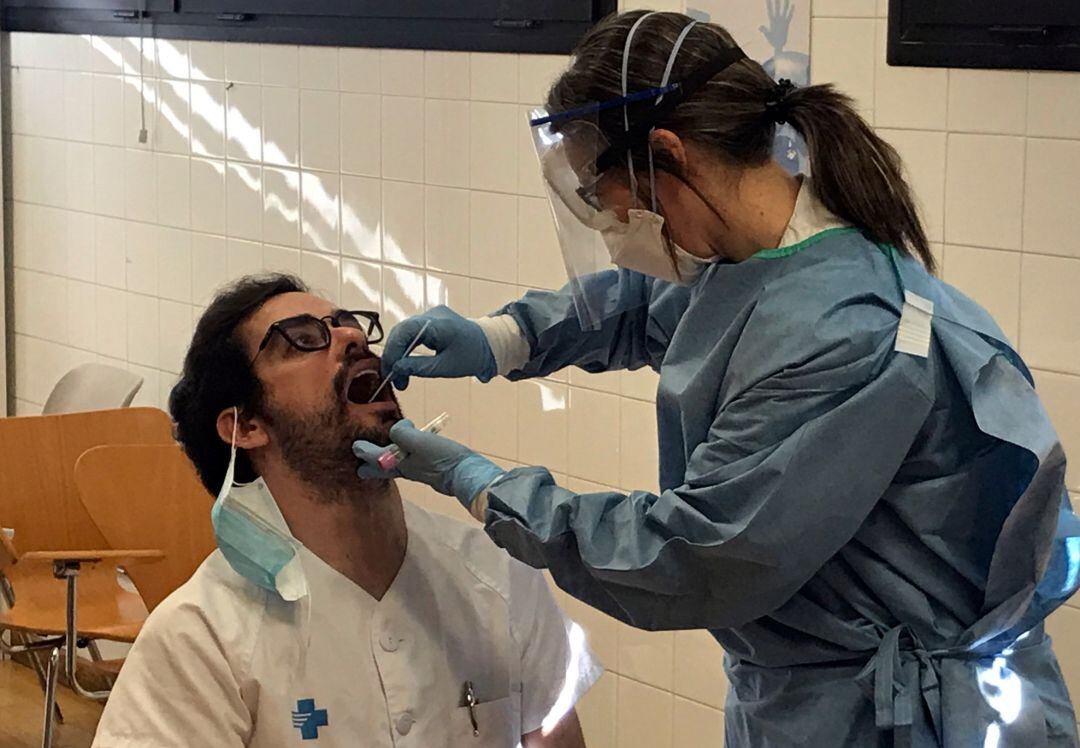 Una profesional sanitaria realiza una prueba de coronavirus a un compañero.
