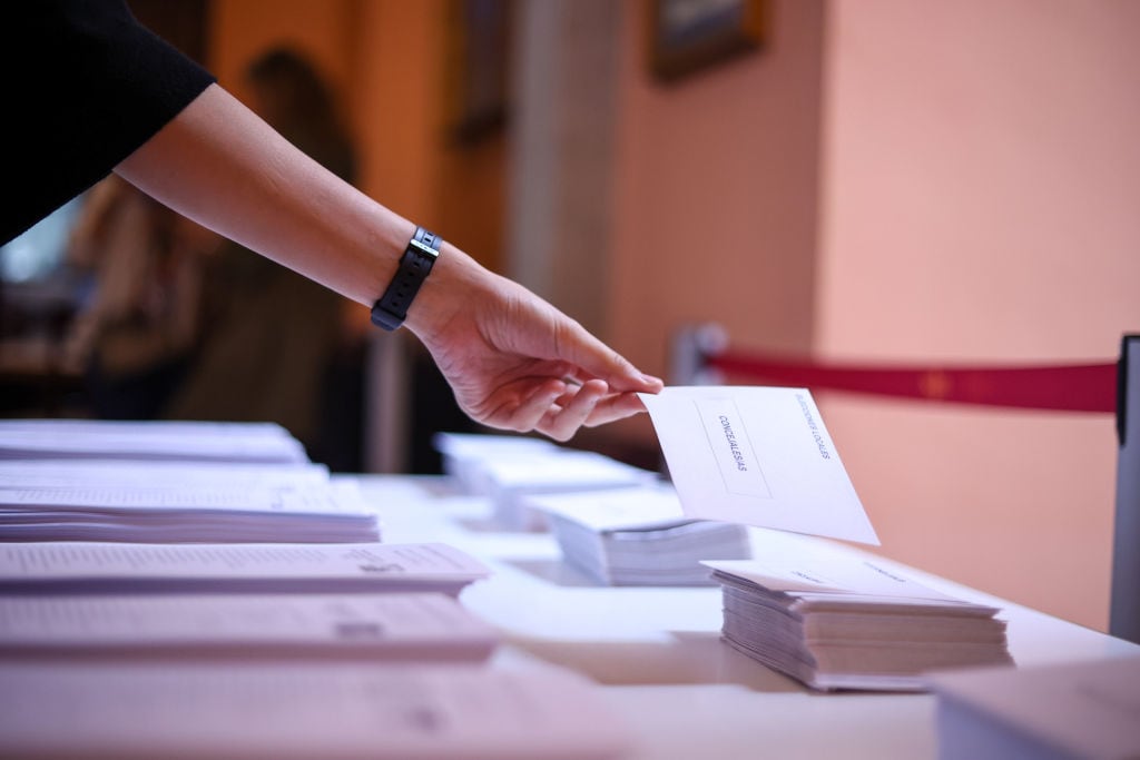 Un elector coge un sobre en un colegio electoral.