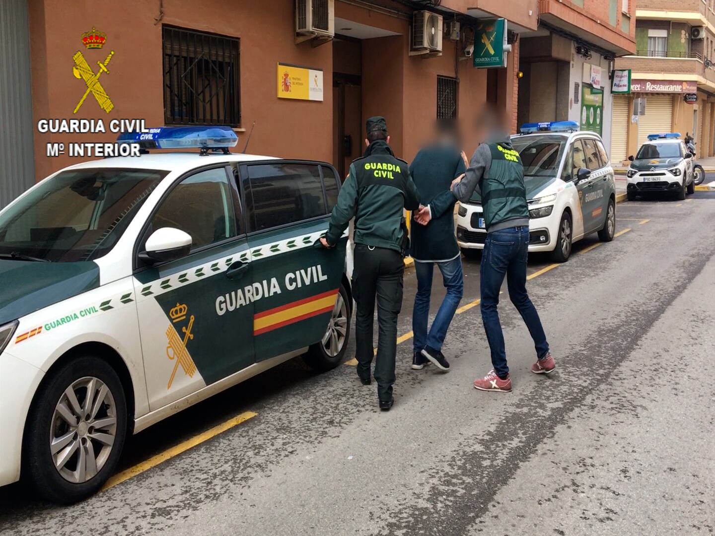 Dos guardias civiles llevan al cuartel a uno de los detenidos.