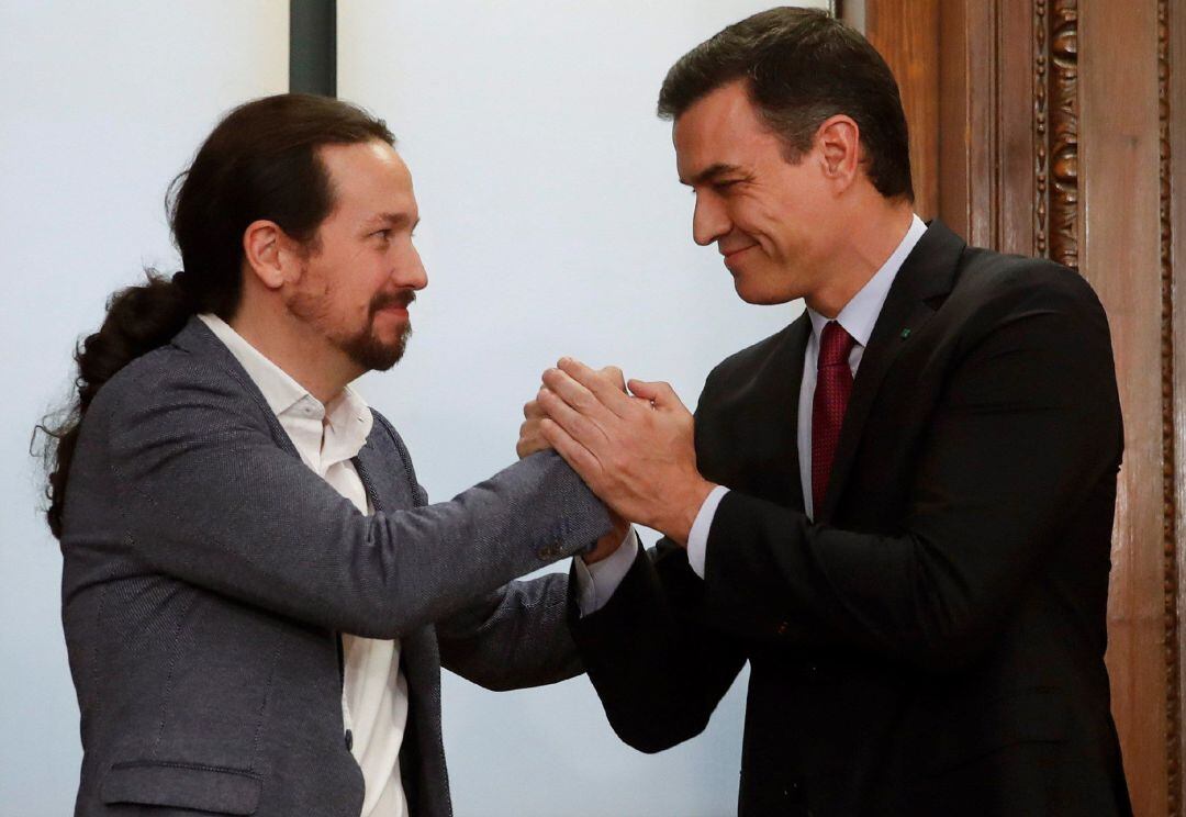 El candidato a la investidura, Pedro Sánchez (d), y el líder de Podemos, Pablo Iglesias (i), estrechan sus manos tras el acto de firma del acuerdo programático con las principales medidas que tomará el futuro Gobierno de coalición