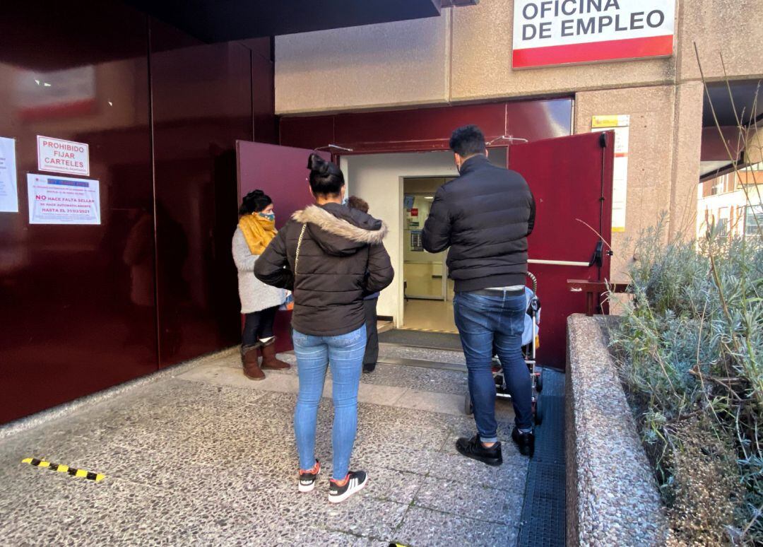 Varias personas frente a una oficina de empleo.