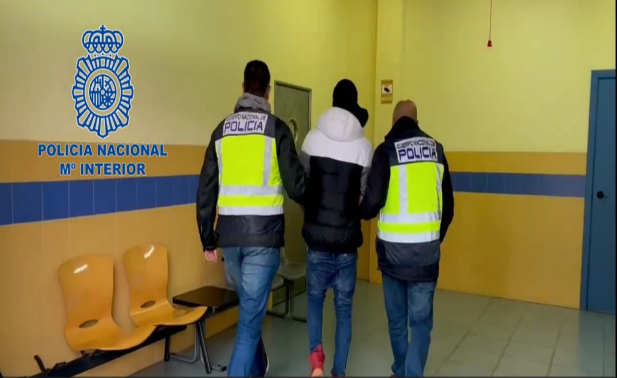 Dos agentes conducen a uno de los detenidos a las dependencias policiales.