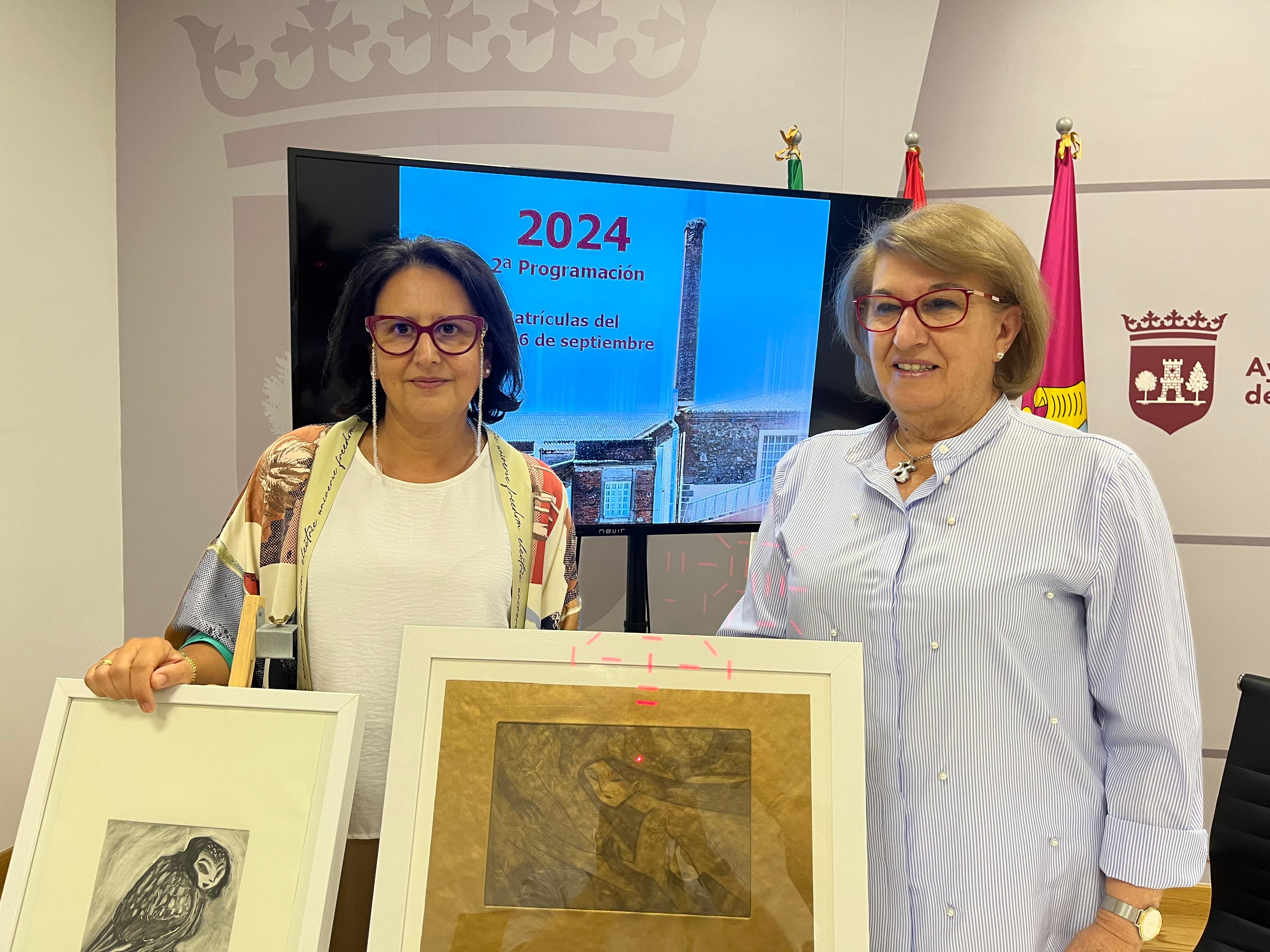 Yolanda Amor, coordinadora de cursos, y Maria Luisa Bermejo, concejala de cultura, posan junto a láminas realizadas por la Universidad Popular.