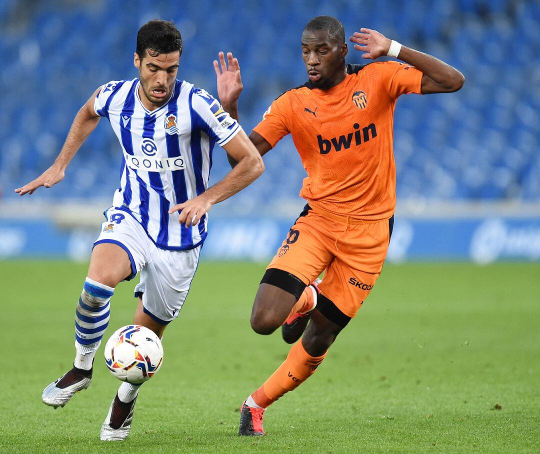 Mikel Merino of Real Sociedad runs with the ball under pressure from Geoffrey Kondogbia of Valencia CF 