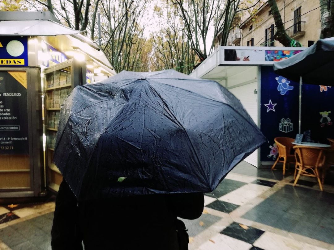 Archivo - Un hombre pasea por la Rambla de Palma bajo un paraguas un día de lluvia.