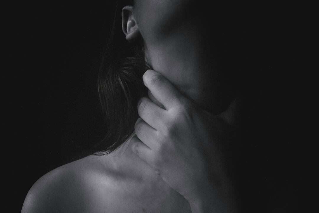 Foto de archivo de una persona agarrándose la garganta.