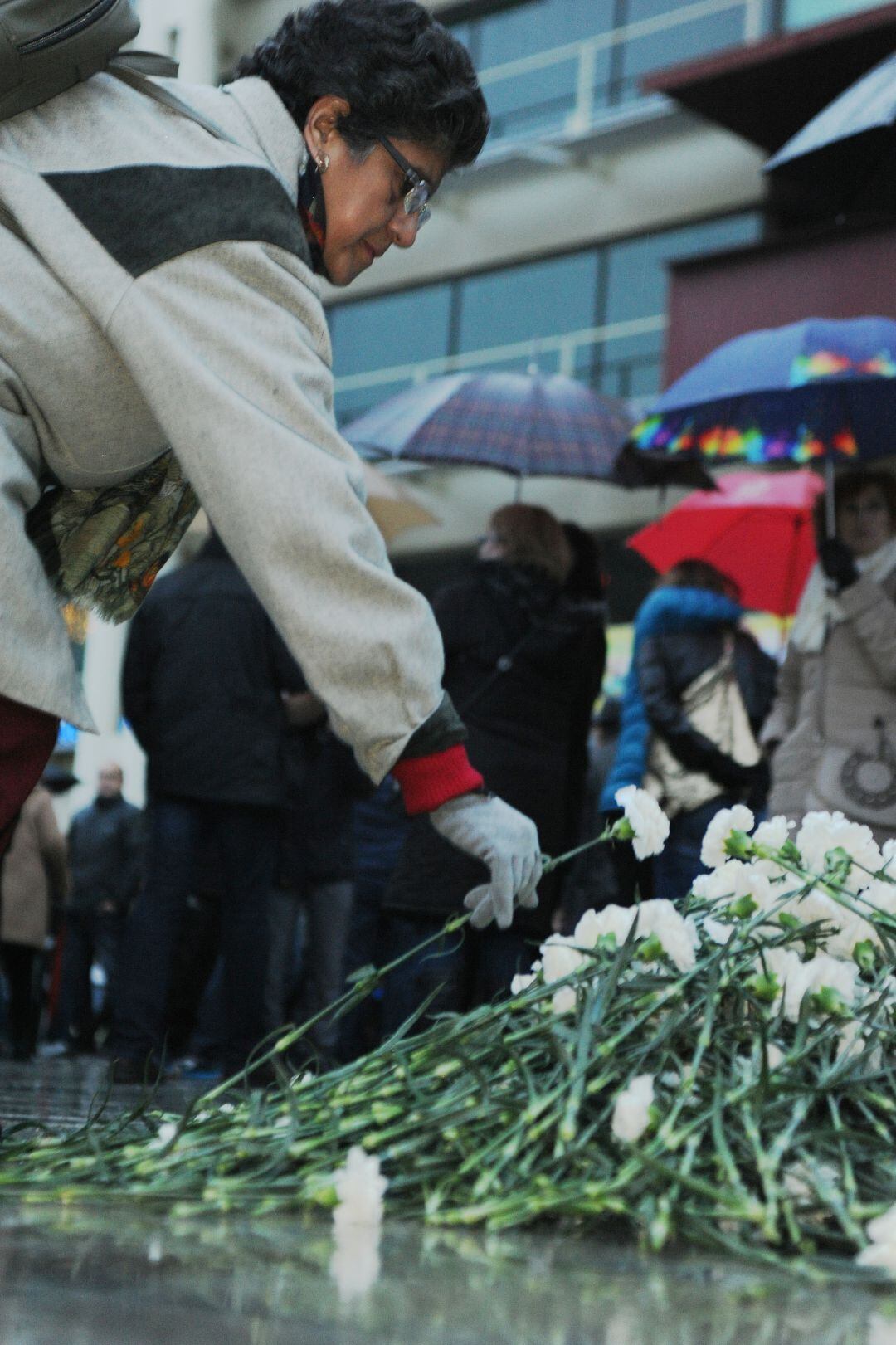Una mujer deposita una flor en una concentración por una víctima de violencia machista frente al ayuntamiento de Fuenlabrada.