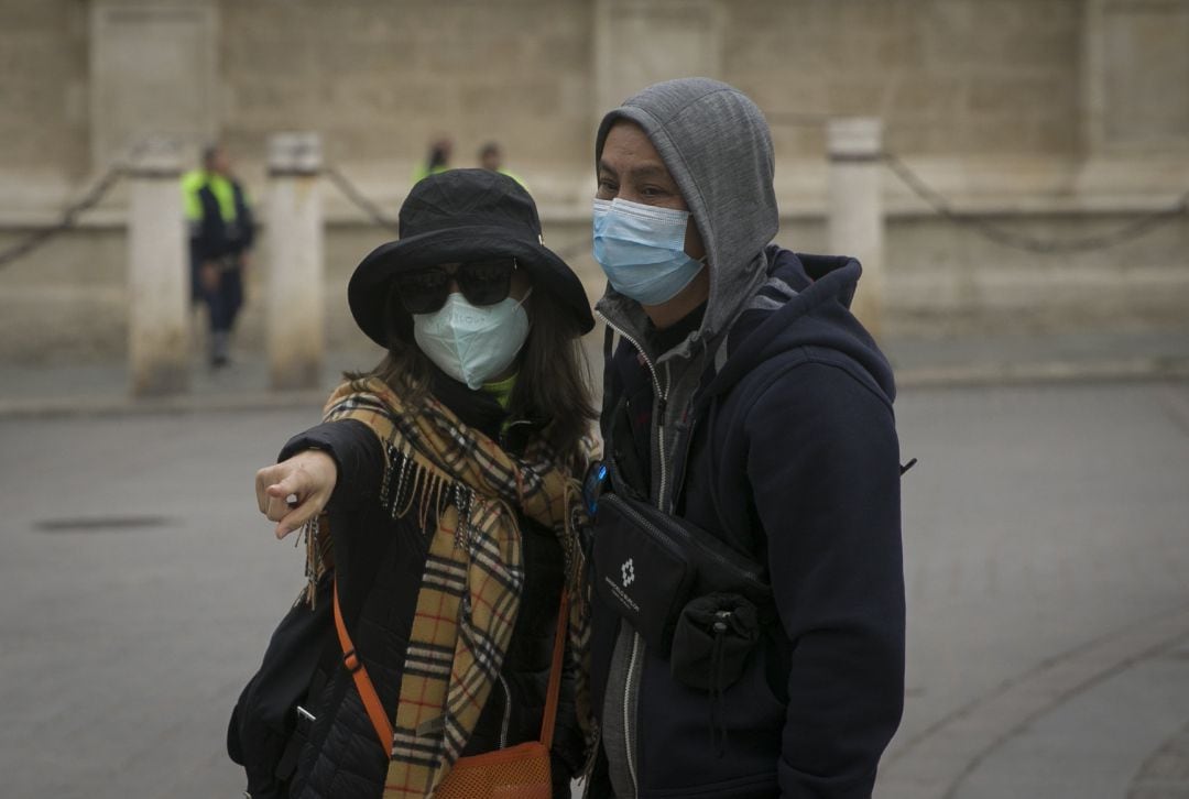 Dos turistas con mascarillas para evitar el contagio por coronavirus.