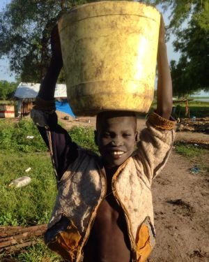 Un niño sonrié mientras transporta agua