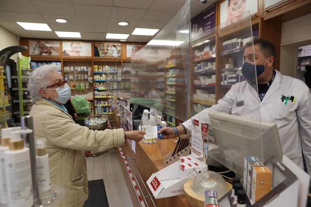 Una anciana recoge una mascarilla FFP2 en la farmacia situada en Carabanchel, en Madrid. Archivo.