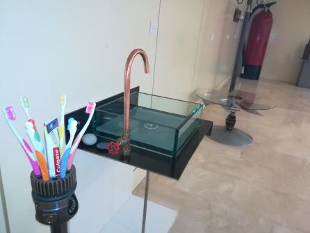 Un portacepillos en primer plano y un lavabo realizado con materiales que habían sido descartados