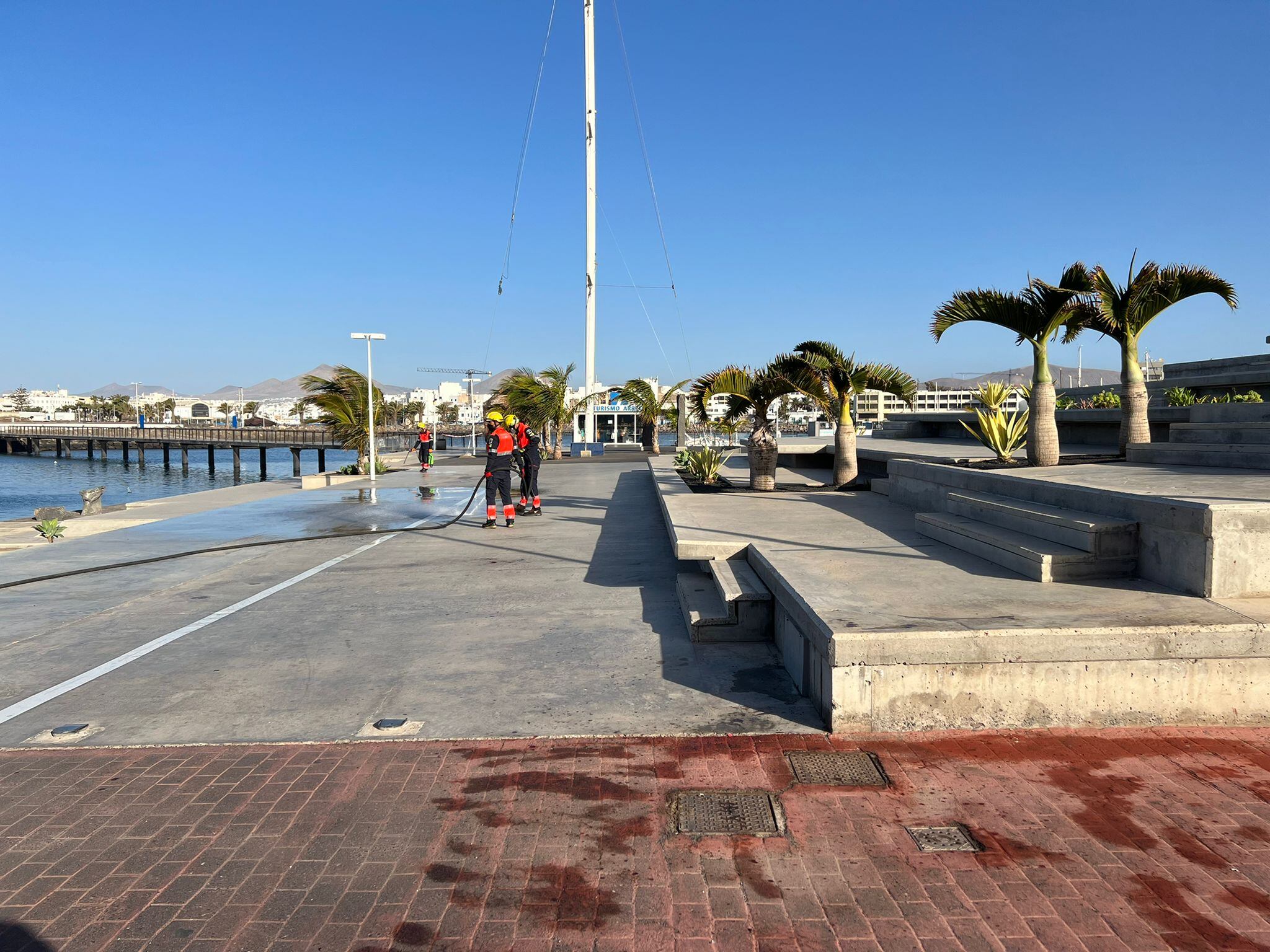 Los bomberos de Lanzarote limpiando los restos de sangre tras la pelea en el puerto deportivo de Arrecife.