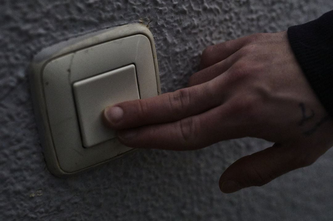 Un hombre toca un interruptor de luz.