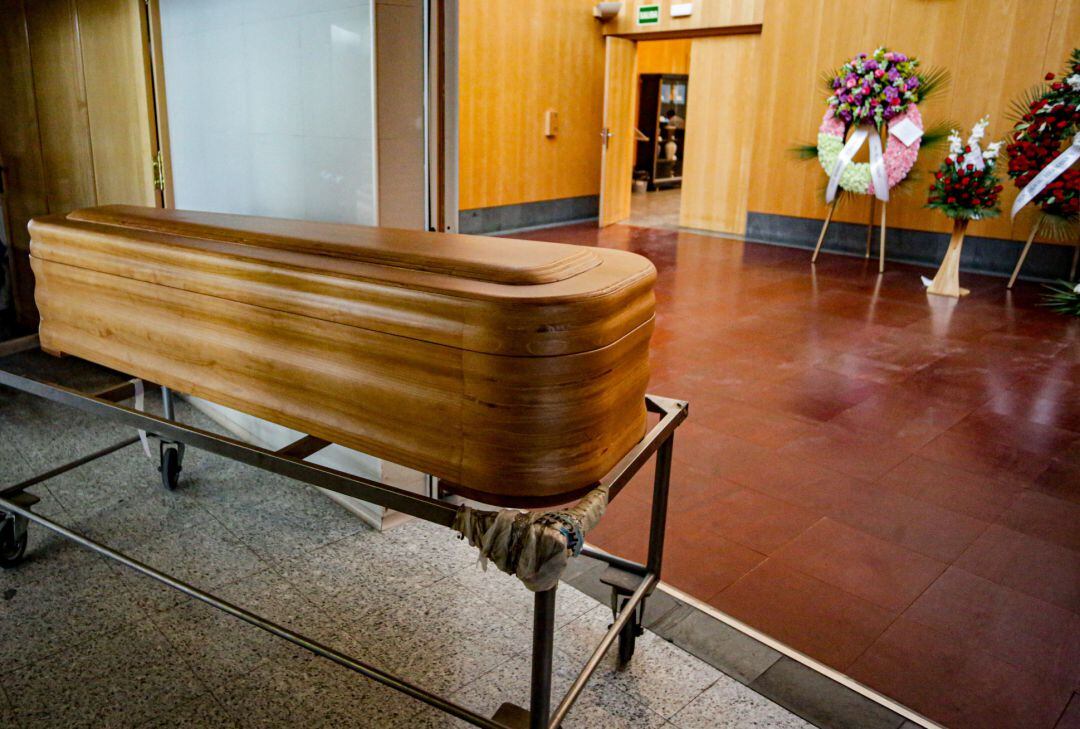 Un ataúd junto a varias coronas de flores fúnebres en el Tanatorio Crematorio Mémora Coslada.