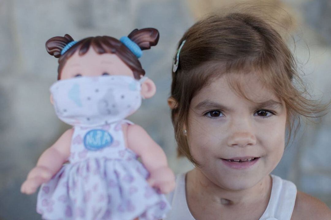 Una niña con enfermedad intestinal junto a una muñeca que desde la asociación venden para dar visibilidad a su trabajo