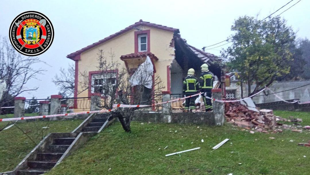 Dos efectivos del Cuerpo de bomberos de Santander junto a la casa en la que se ha producido la explosión.