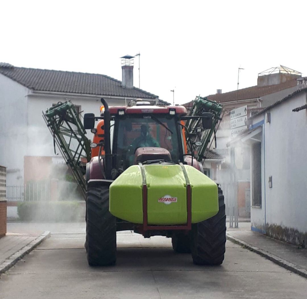 Un tractor trabaja para desinfectar las calles de un pueblo.