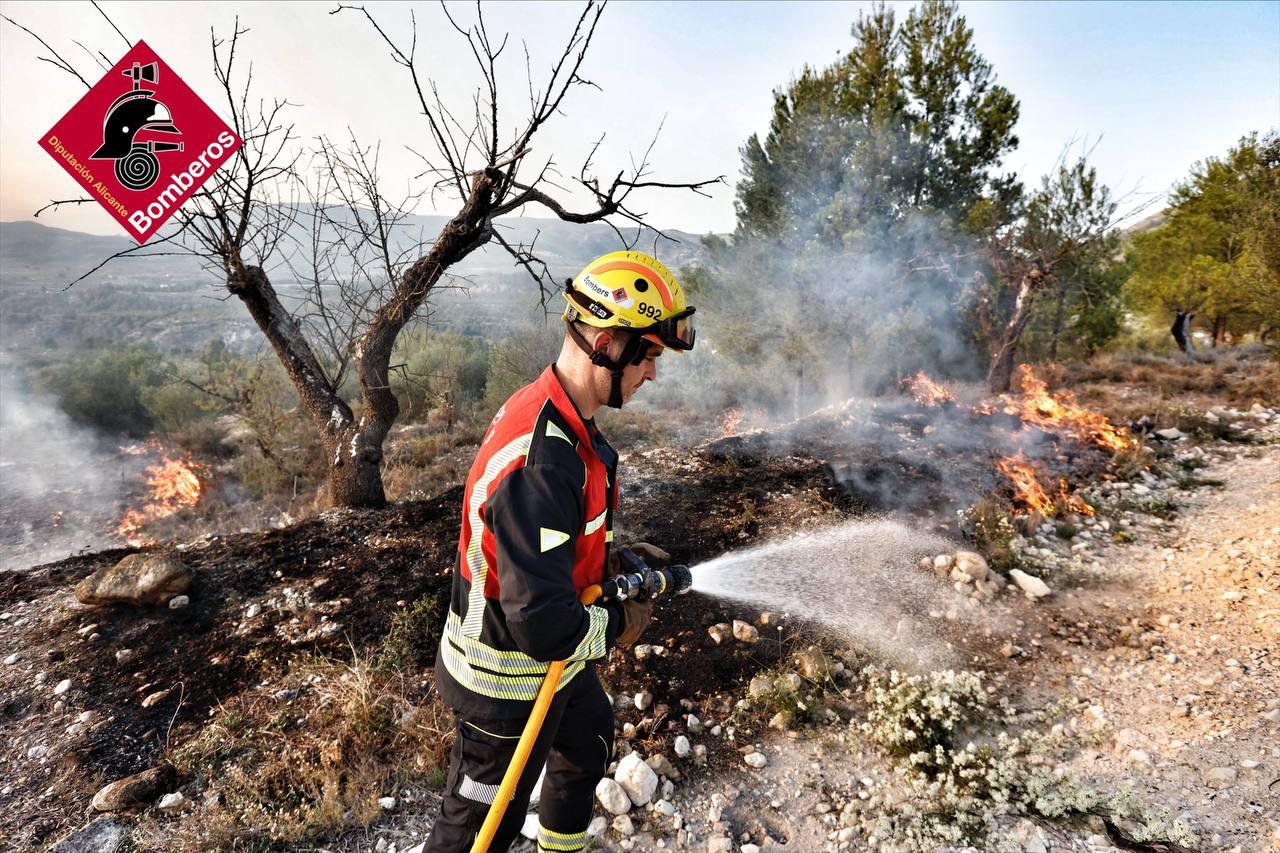 Un bombero extinguiendo las llamas en el incendio declarado en Ares del Bosque, pedanía de Benasau, y se ha extendido hacia Penàguila.