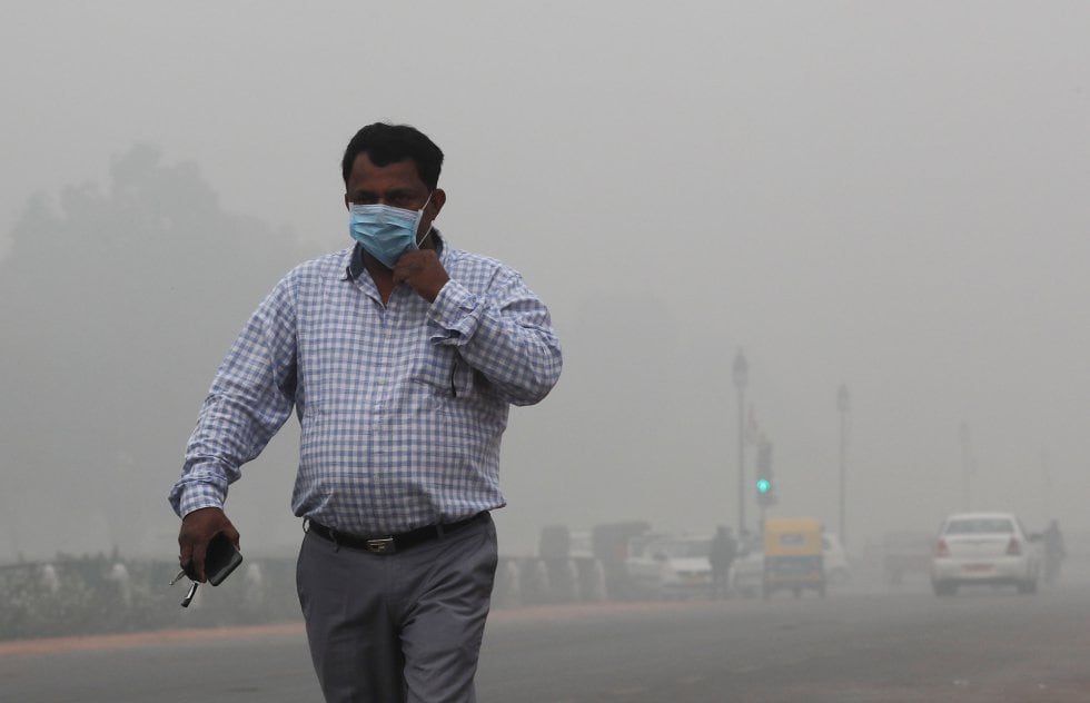 Un hombre con una máscara camina en una mañana de niebla en Nueva Delhi