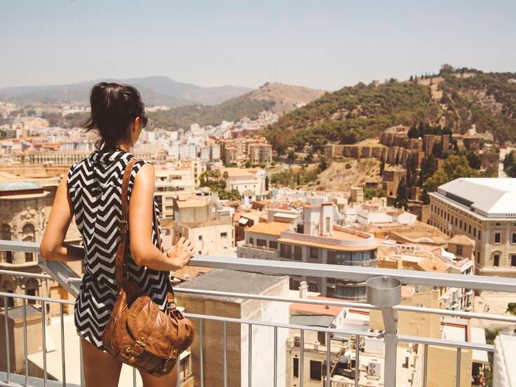 Una joven observa una vista en altura de Málaga / Lechatnoir