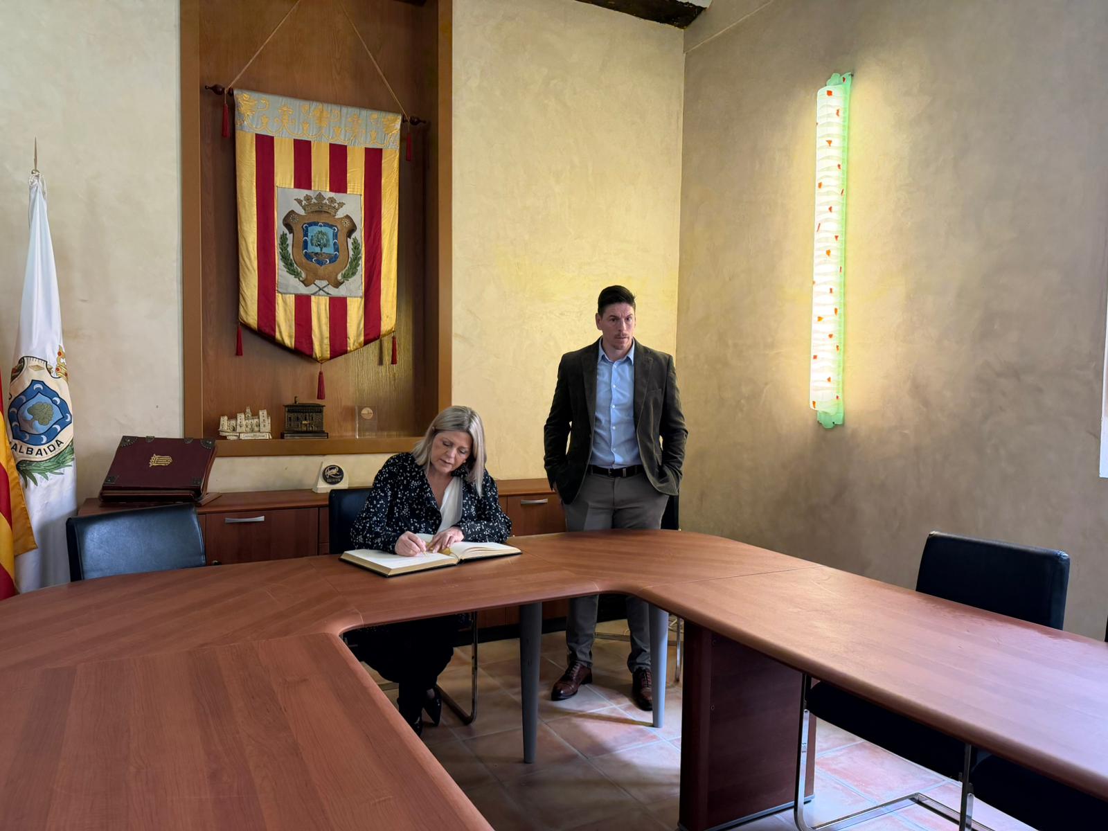 Carmen Ortí, Consellera de Educación, Cultura y Universidades firmando el libro de honor del Ayuntamiento de Albaida, acompañada por el alcalde.