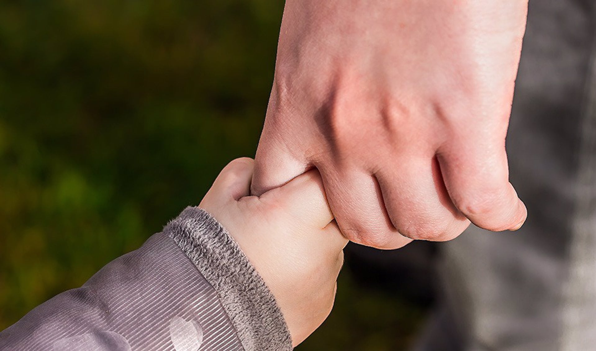 Un menor agarra la mano de un adulto