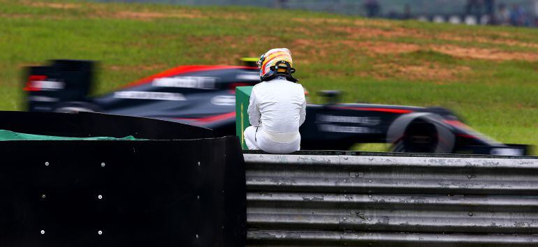 Fernando Alonso ve pasar a su compañero Jenson Button tras una avería en los entrenamientos del GP de Brasil.