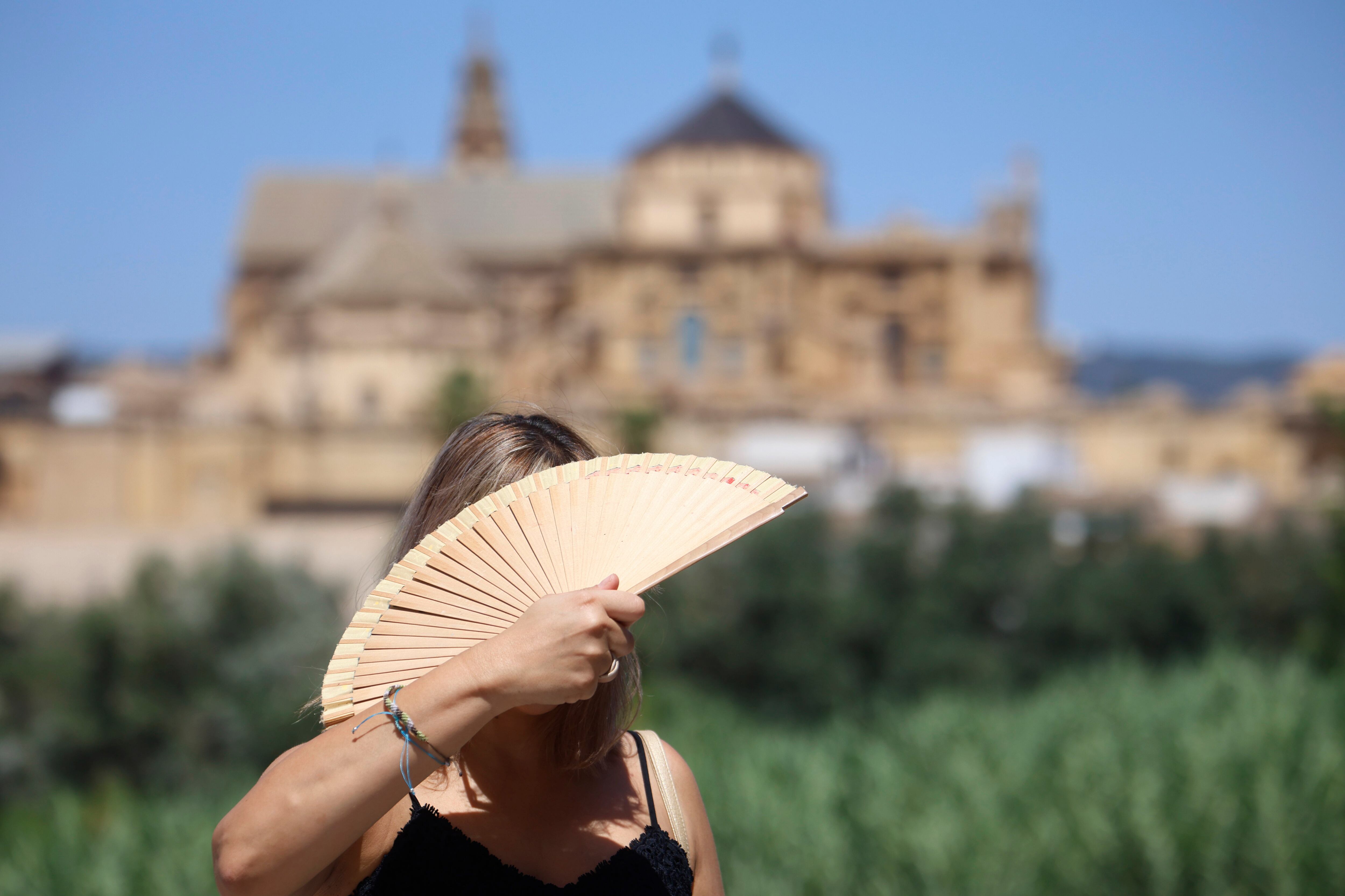 Una turista se abanica en el puente romano de Córdoba este viernes. El puente de agosto comienza con España inmersa en una larga ola de calor.