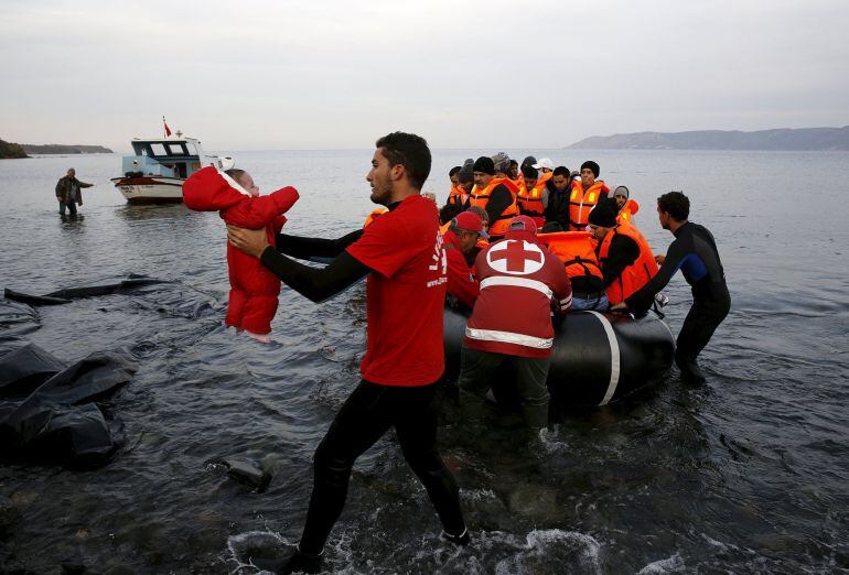 Un voluntario de la Cruz Roja traslada a un bebé sirio que ha llegado en una embarcación de plástico junto con otros compatriotas a la isla griega de Lesbos. 