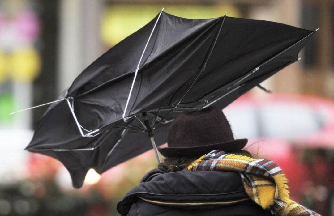 Un hombre se protege de la lluvia y el viento. 