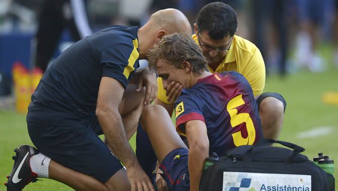 Marc Muniesa del FC Barcelona (C) recibe asistencia médica durante el partido amistoso disputado ante el Hamburger SV en el Imtech Arena de Hamburgo
