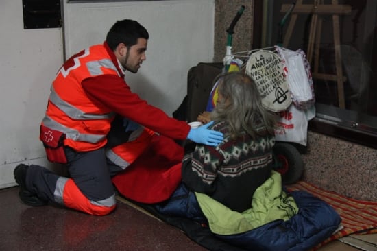 Un voluntari de Creu Roja amb un indigent