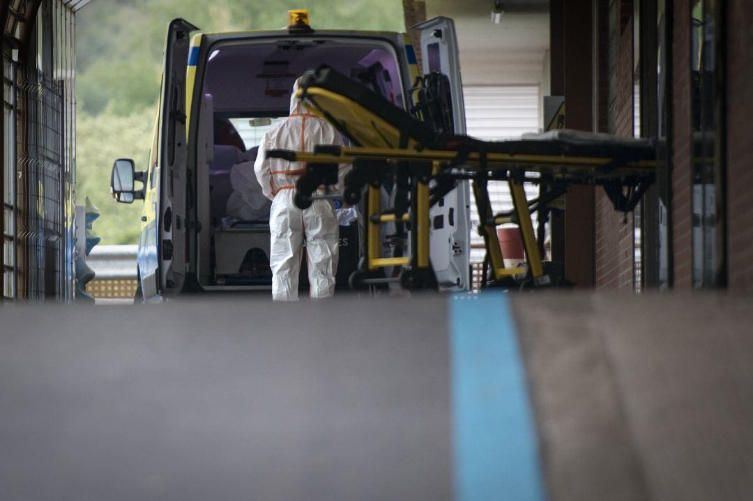 Un trabajador sanitario ayuda a un paciente en una ambulancia estacionada en la entrada de Urgencias del Hospital Universitario Doctor Josep Trueta (Girona)