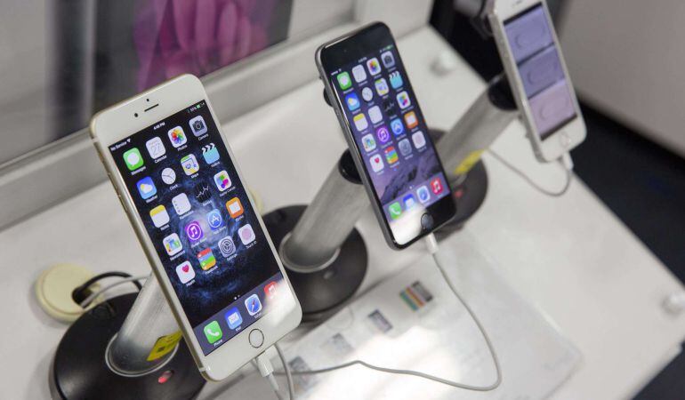 Los modelos iPhone 6 Plus, iPhone 6 y iPhone 5S sobre un expositor de Apple