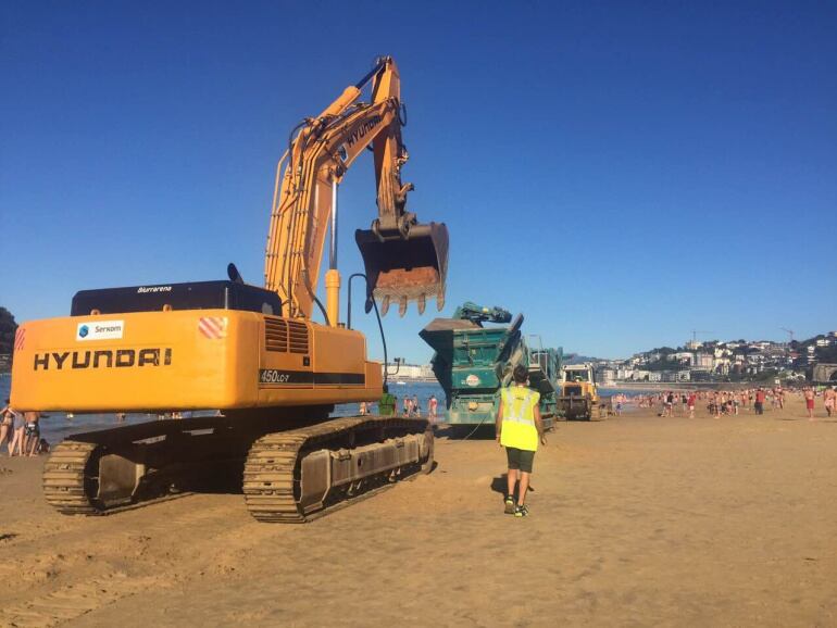 Imagen de las máquinas (excavadora y despedregadora) entrando en la playa de Ondarreta