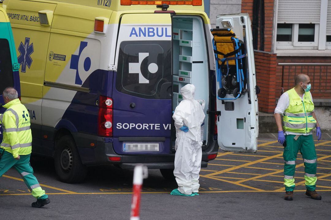 Varios sanitarios protegidos, junto a una ambulancia