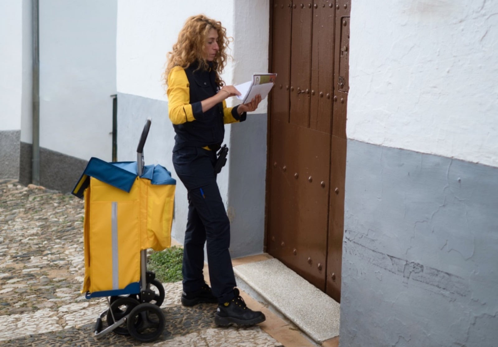 Una trabajadora de Correos a punto de entregar unos paquetes.