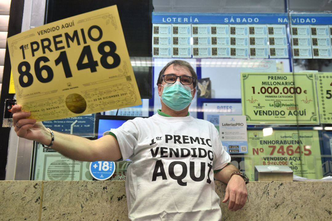 Javier Moñino, empleado de la administración situada en la zona del AVE de la Estación de Atocha, posa con un décimo gigante mientras celebra que ha vendido parte del número 86148 correspondiente al &#039;Gordo&#039; del Sorteo Extraordinario de la Lotería de Navidad, a 22 de diciembre de 2021, en Madrid (España)