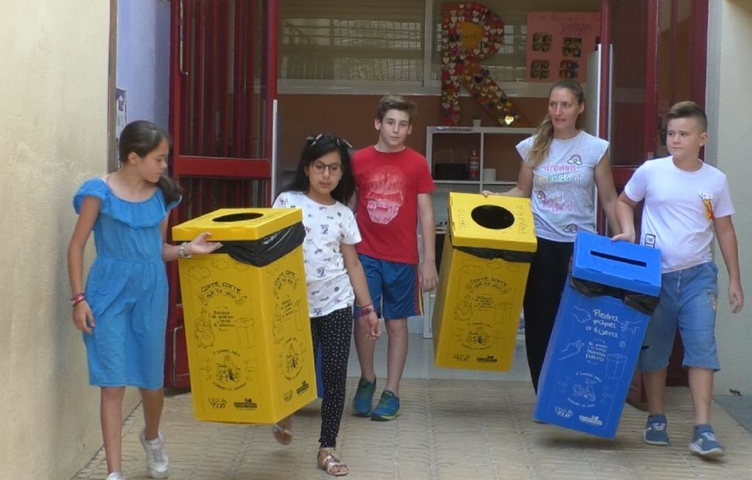 La profesora Beatriz Cruz con varios alumnos portando los cubos de reciclaje