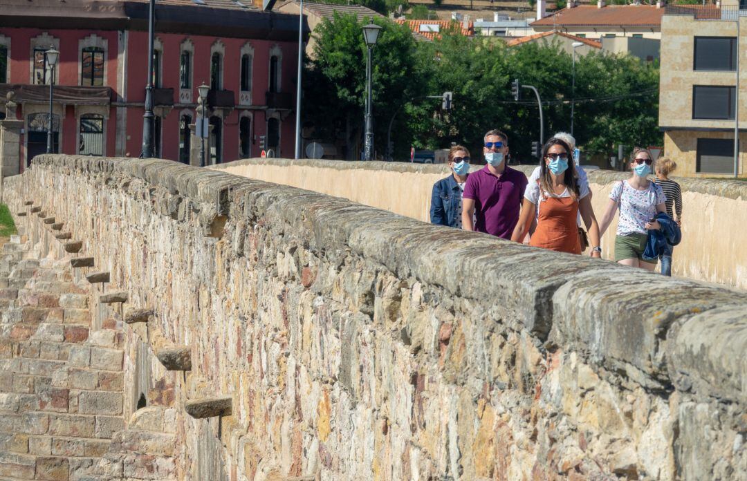 Imagen de turistas, pocos, paseando por el Puente Romano.