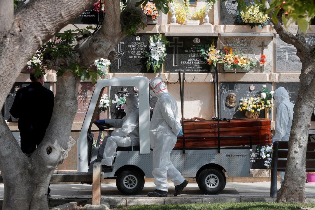 Personal del cementerio del Cabañal transporta un féretro durante el entierro al que han podido asistir tres familiares, el máximo autorizado en las comitivas a los cementerios para enterramiento o despedida de cremación a causa del estado de alarma decretado por el Gobierno por la pandemia del coronavirus