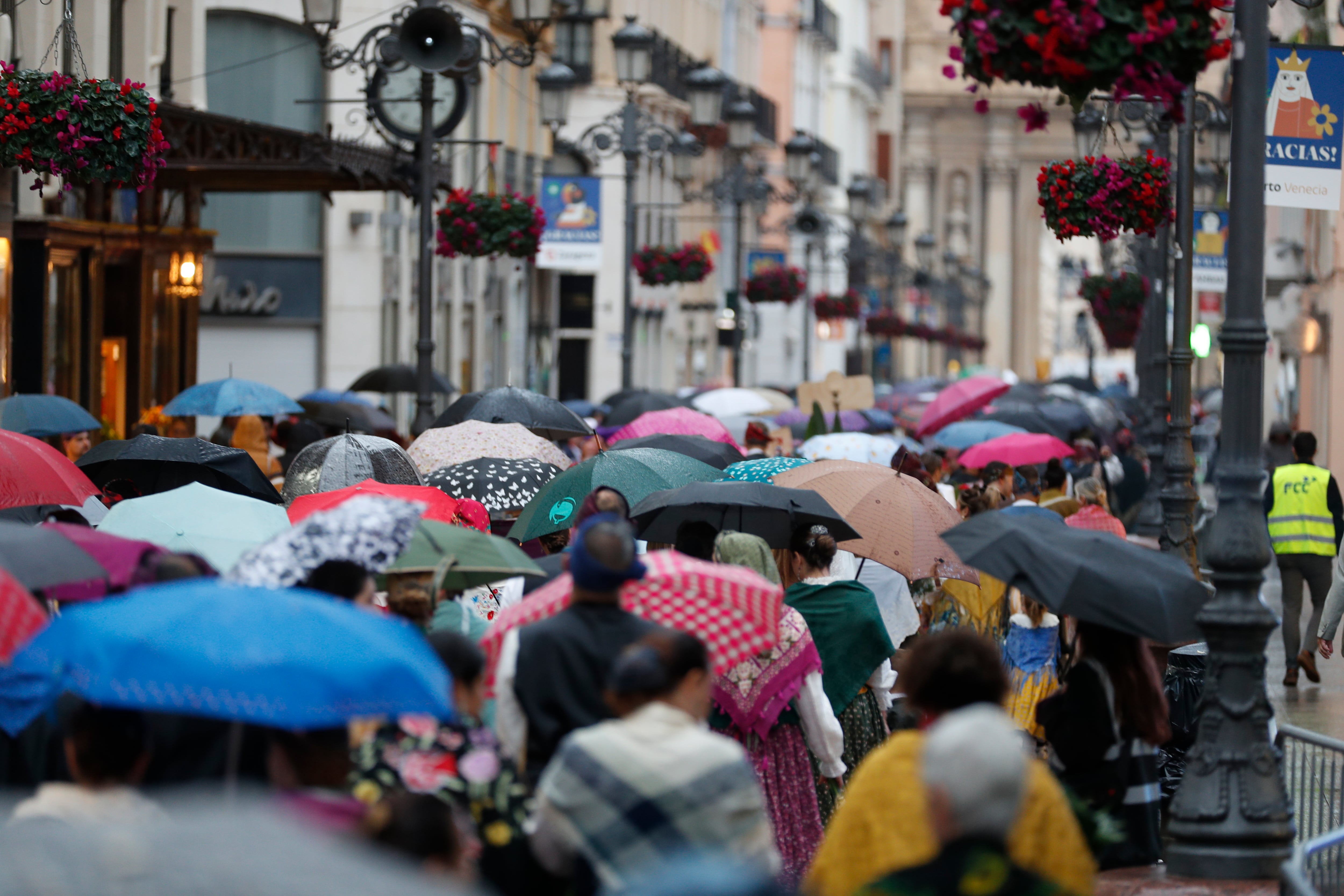 ZARAGOZA, 12/10/2024.- Varias personas se dirigen hacia la Plaza del Pilar para participar en la tradicional Ofrenda de Flores a la Virgen del Pilar este sábado en Zaragoza, en una jornada marcada por la lluvia. EFE/ Javier Belver
